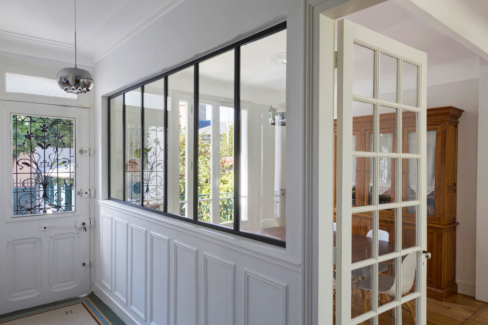 Cloison vitrée de style atelier d'artiste installée dans l'entrée d'une maison